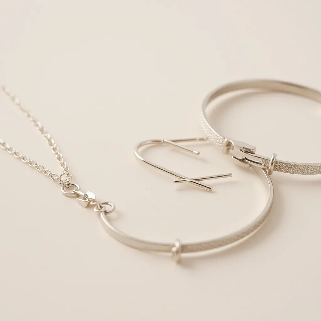 Polished silver chain and small earrings arranged on a clean neutral background
