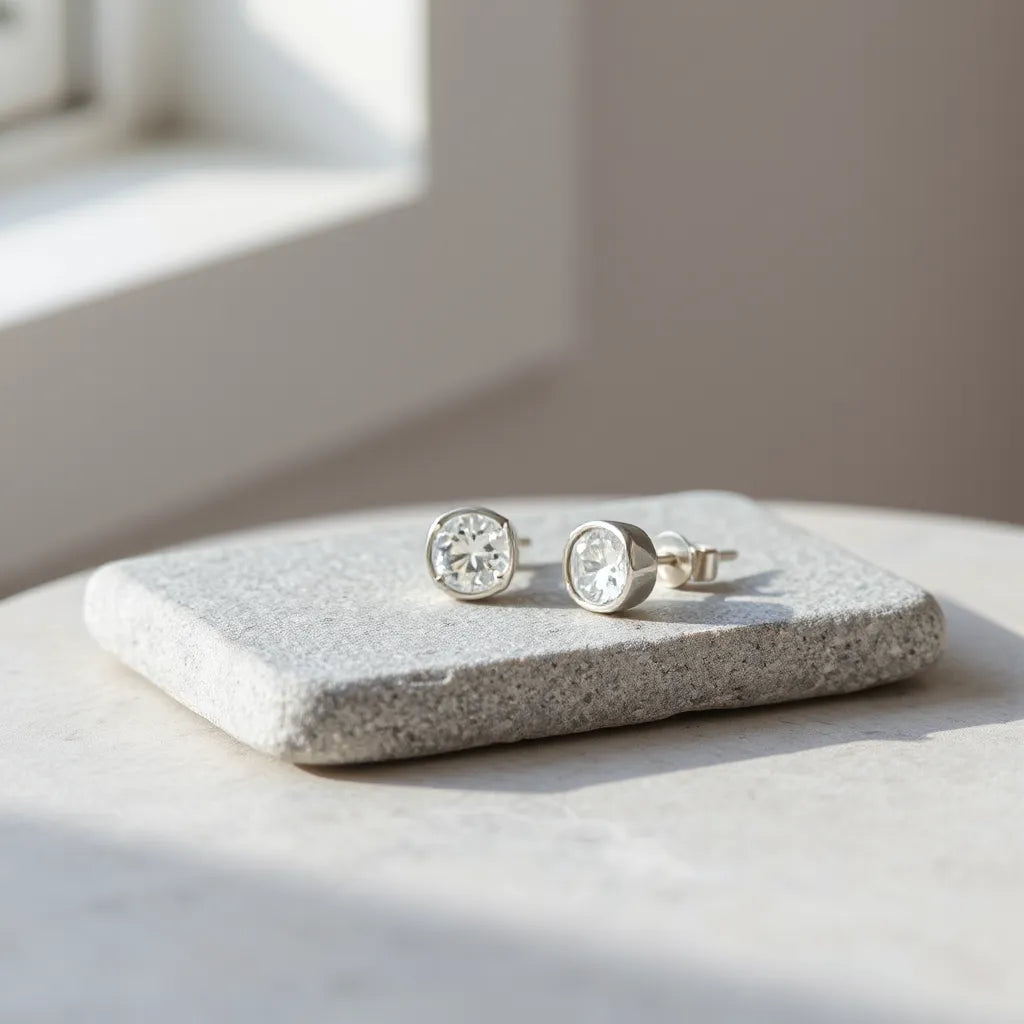 Pair of solid 925 sterling silver stud earrings on a light stone surface with soft natural lighting