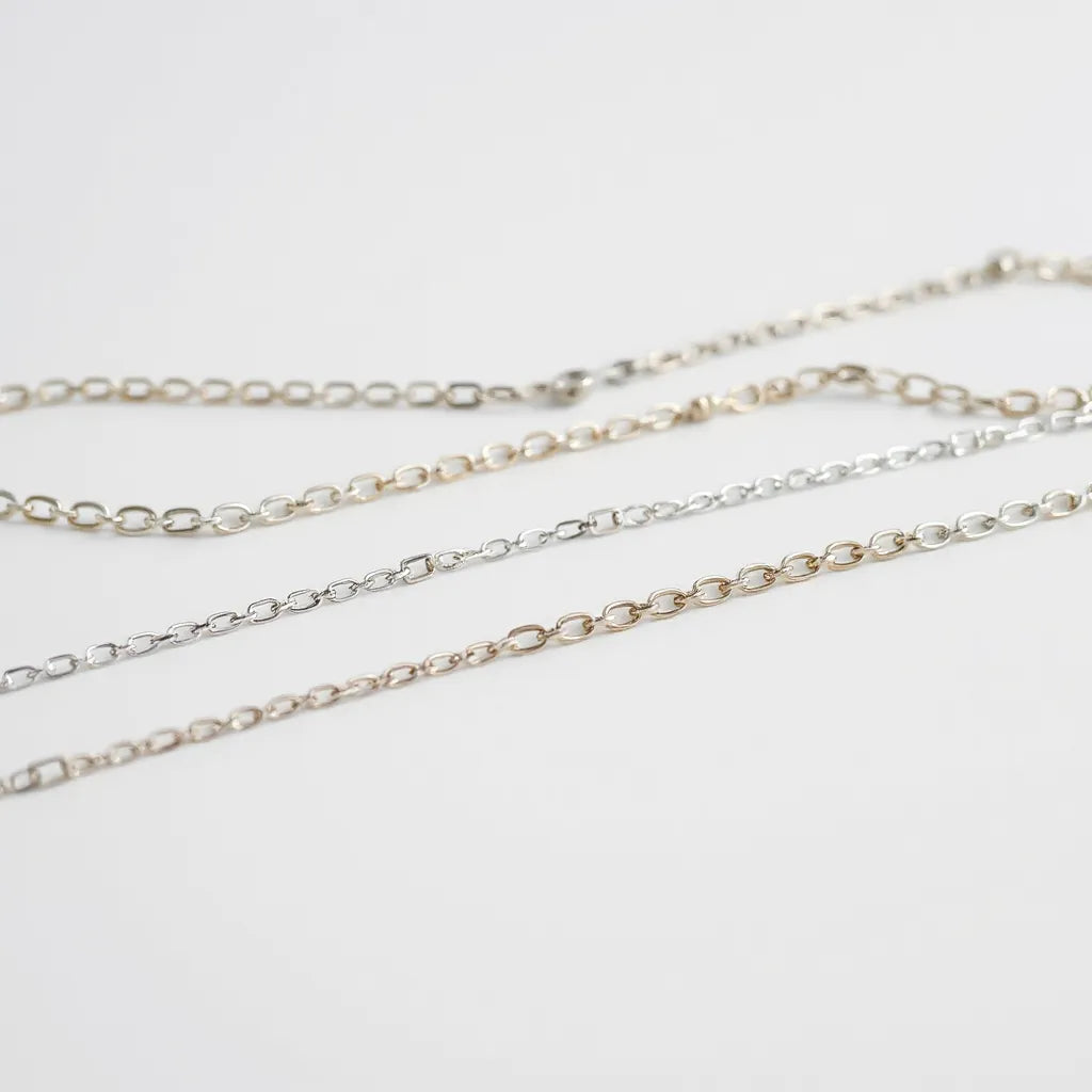Assorted solid sterling silver chains displayed on a neutral background with soft reflections